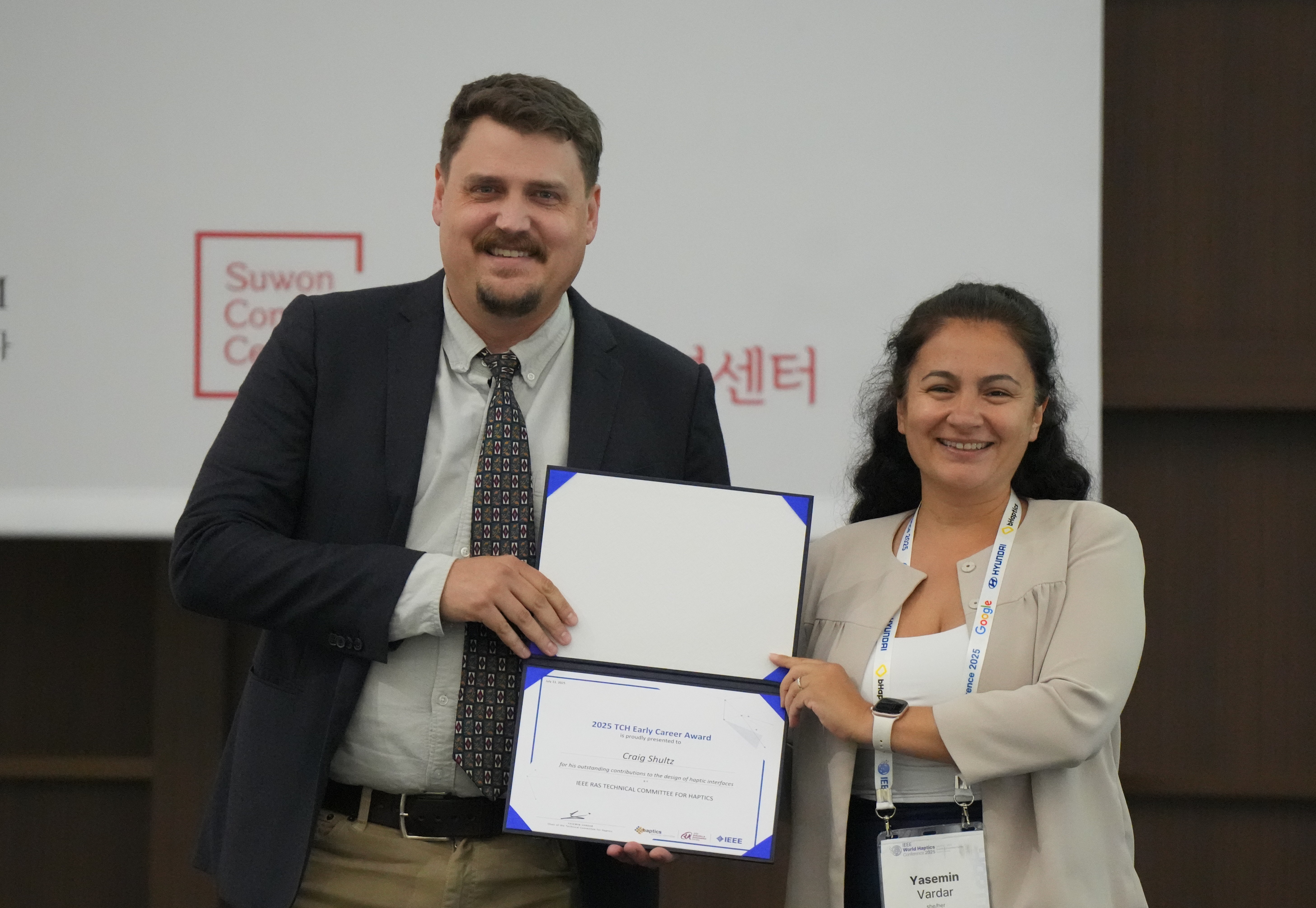 Craig Shultz receiving the TCH Early Career Award certificate from Yasemin Vardar, chair of the Technical Committee for Haptics.