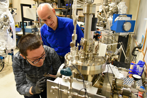 Postdoctoral researcher Gang Wang loading a sample into the system used to perform the nanotube crosslinking operation while Joseph Lyding looks on.