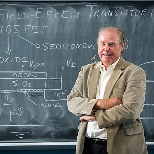 Photo of Jean-Pierre Leburton, Illinois Grainger Engineering Gregory Stillman Professor of Electrical and Computer Engineering Emeritus, with arms crossed in front of a chalkboard