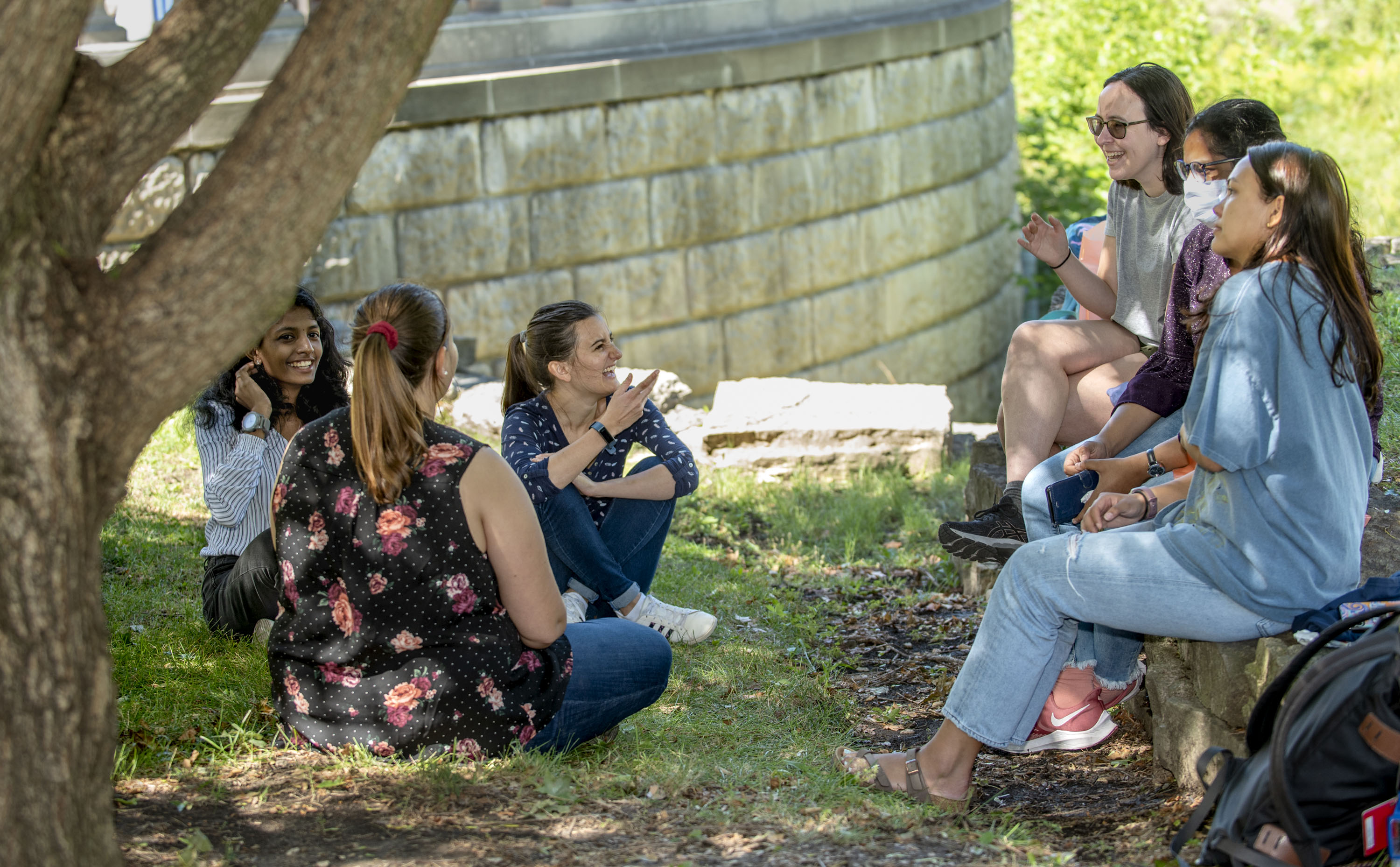 Graduate students sit on a grassy area of the quad to socialize