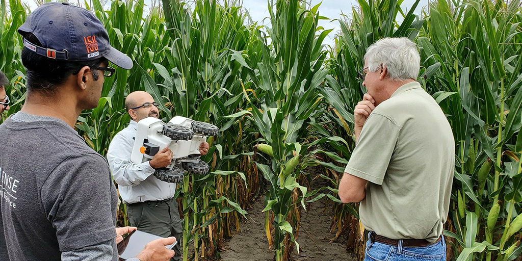 EarthSense founders Chinmay Soman, left, and Chowdhary introducing their robot to a farmer in Farmer City, Illinois. (Photo credit: Knvul Sheikh and Illinios News Bureau)