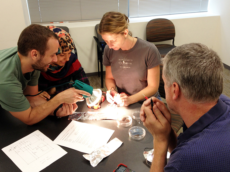 RET teacher Aubrey Wachtel tests her solar cell with the help of graduate students Steve McKeown and Mahsa Kamali. (RET teacher Dan Reid looks on.)