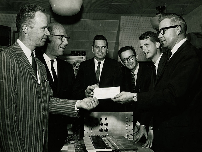 Members of the university accept a grant from the Magnavox Corp. that enabled the HTG to be constructed. James Beauchamp is second from the right. The picture was taken in 1963 when the HTG was only partially constructed. From left to right: Duane Branigan (director of the School of Music) William L. Everitt (dean of the College of Engineering), an unidentified Magnavox employee, Prof. Lejaren Hiller Jr., James Beauchamp, and another unidentified Magnavox employee. Photo Credit: Courtesy of James Beauchamp
