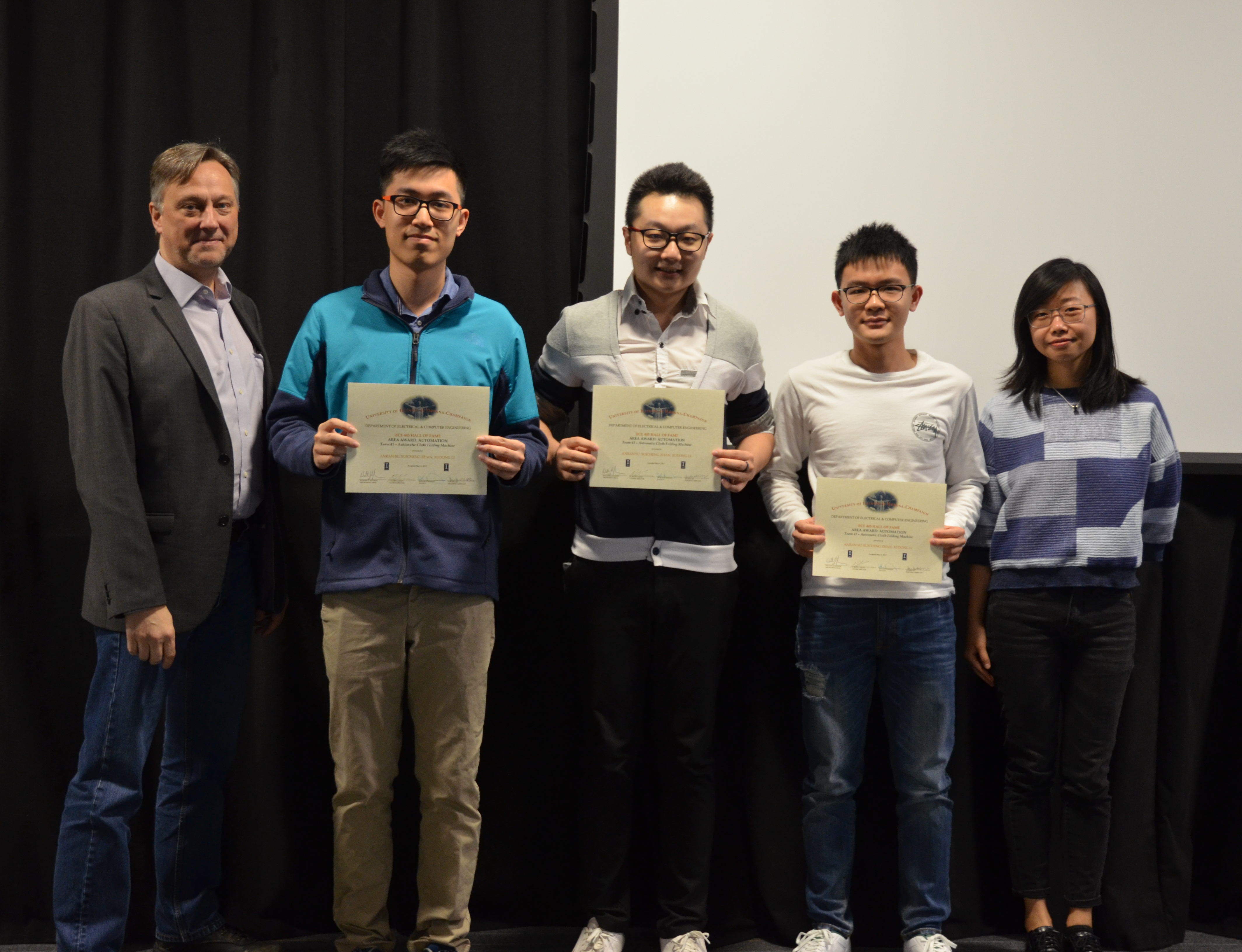 The Area Award for Automation is presented to Anran Su, Suicheng Zhan and Xudong Li for their 'Automatic Cloth Folding Machine.' Also pictured: Professor Hutchinson, Yuchen He (TA).