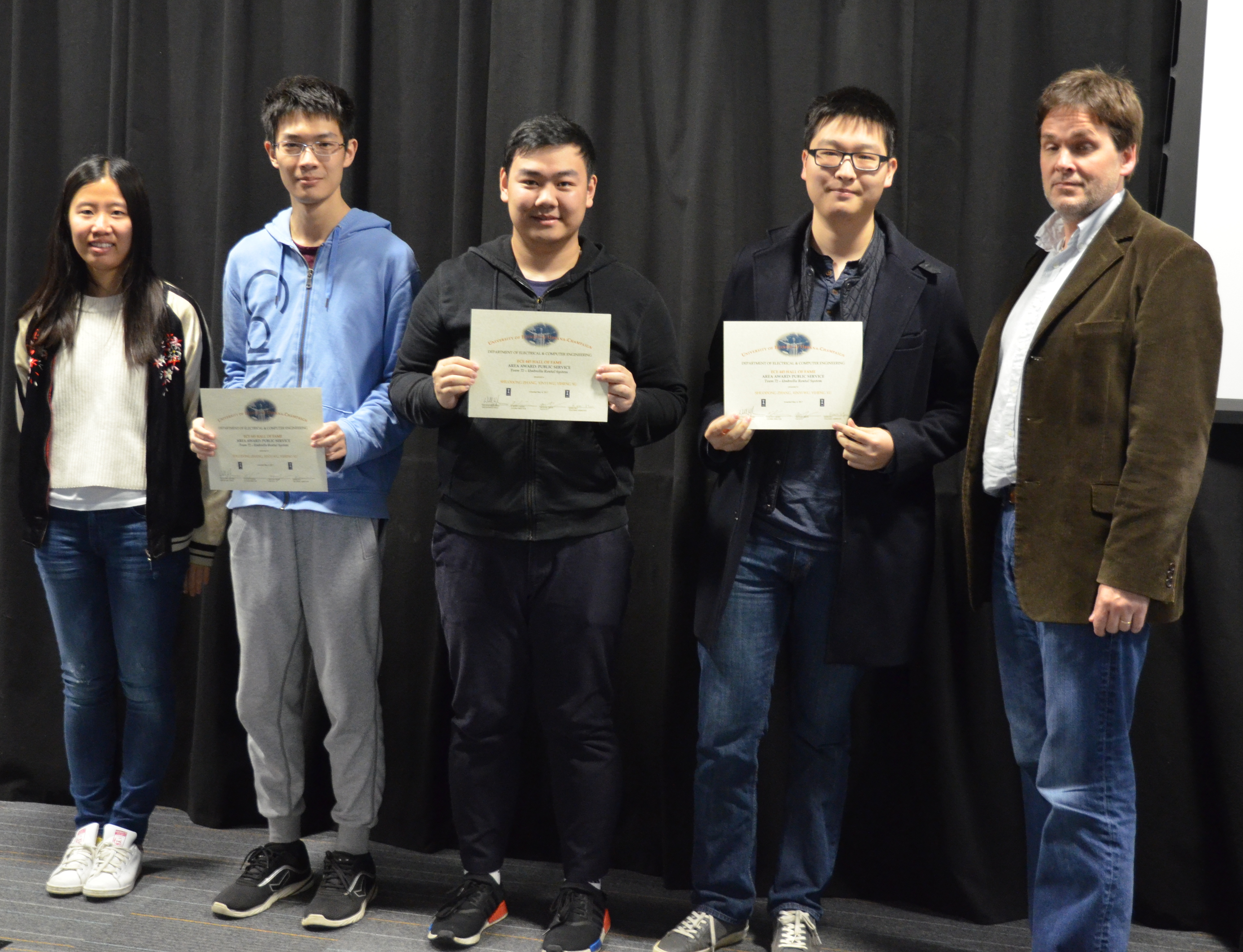 The Area Award for Public Service is awarded to Shudong Zhang, Xinyi Wu, and Yiheng Xu for their 'Umbrella Rental System.' Also pictured: Kexin Hui (TA), Professor Oelze.