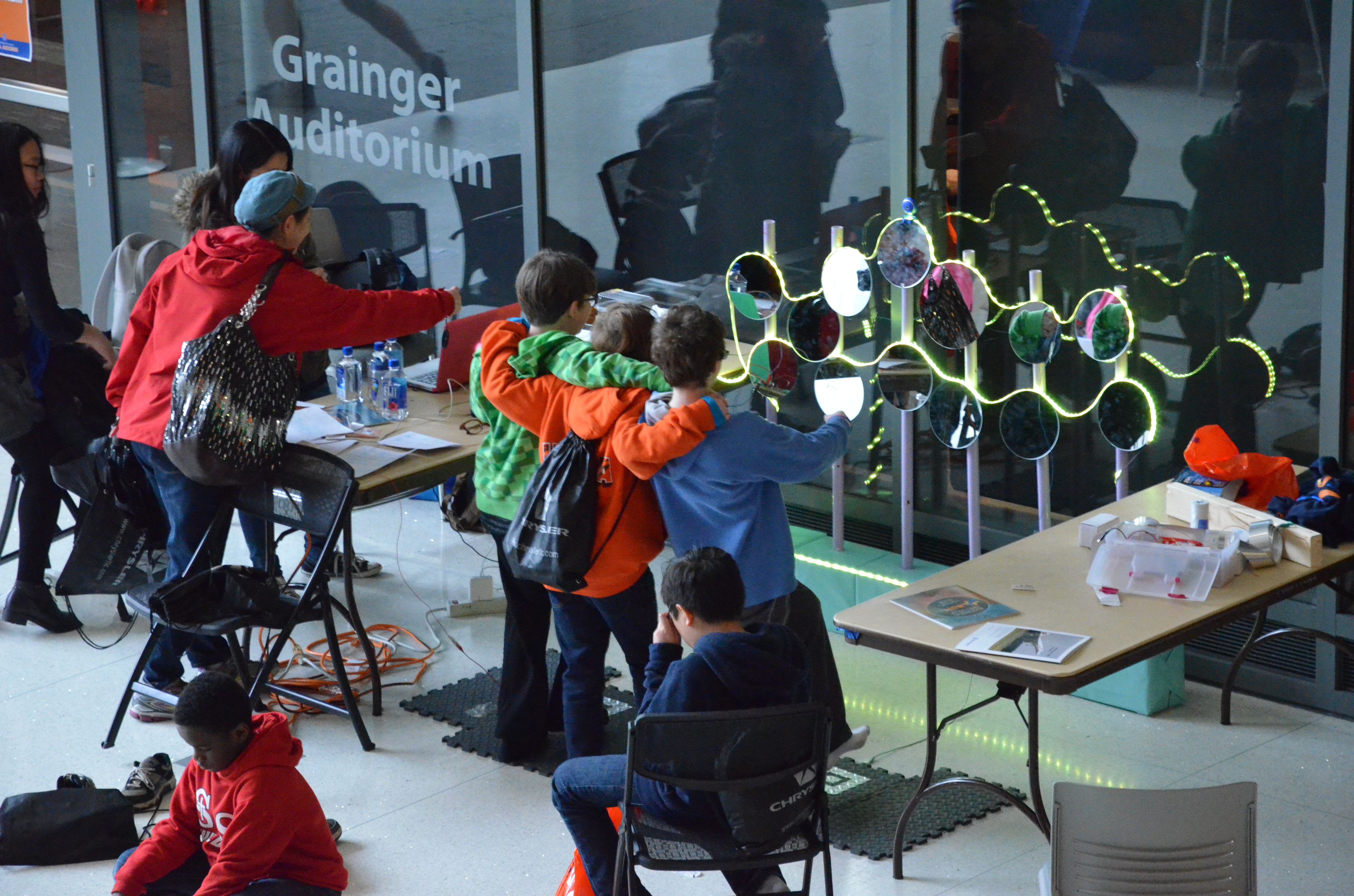 A trio of young students are drawn in by one of the exhibits at Engineering Open House in the lobby of the ECE Building.