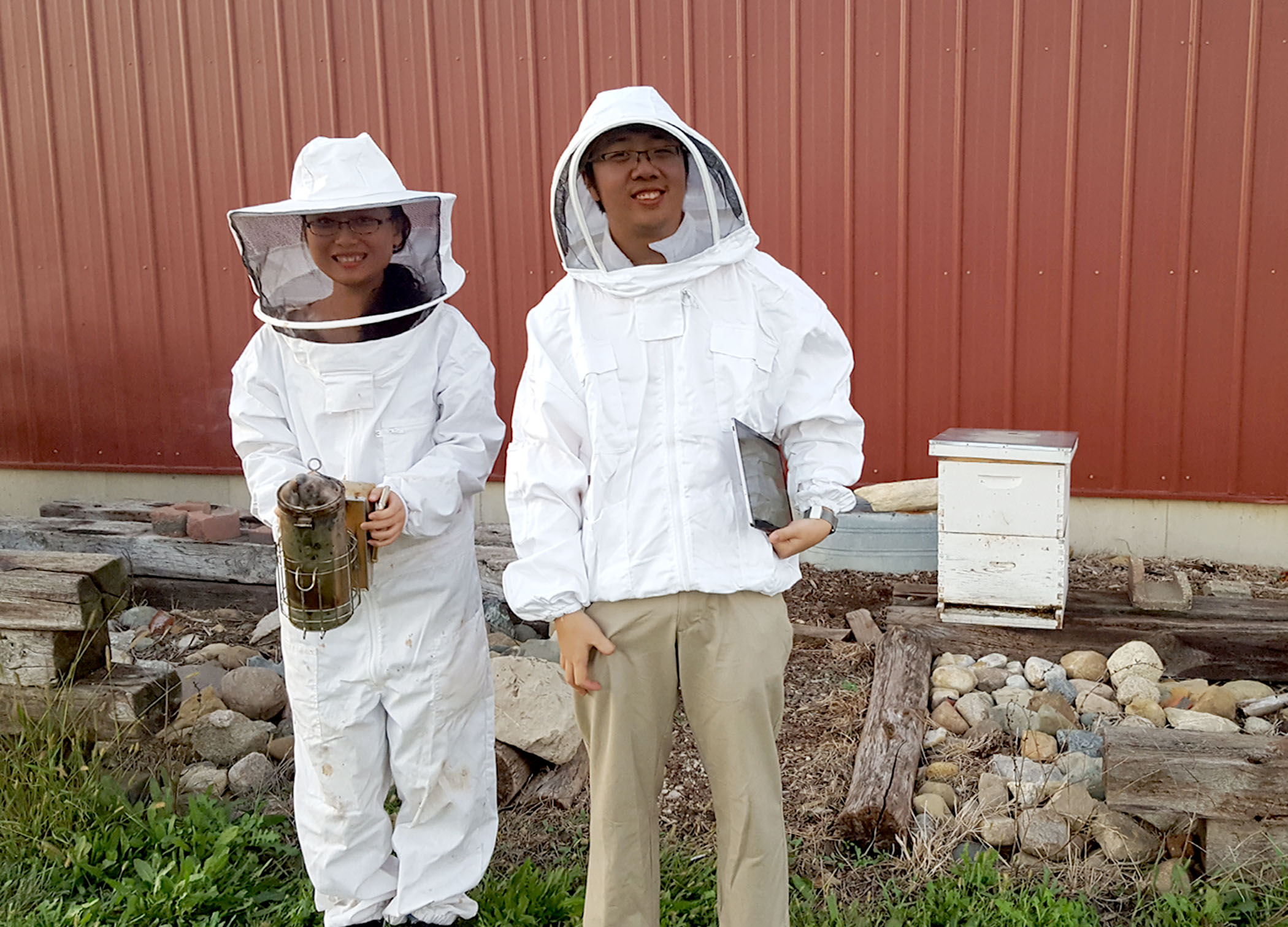 Xiaolin Wu (left) and Jimmy He suit up to install WaggleNet at Schmitz's own beehive.