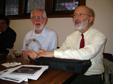 Uribe, at conference in 2007, demonstrates one of his thought-provoking creations: A circuit of one voltage source, five double-pole double-throw switches, and one lamp. A simple, Mobius-like design- explained in the introduction to Uribe's Tractatus- lies behind the circuit's curious behavior. At left is ECE Lecturer Emeritus Paul Weston, who was also on the research staff of BCL.