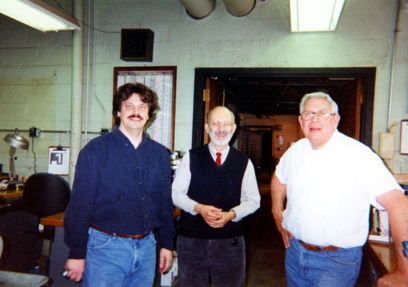 Uribe in the ECE machine shop in Everitt Lab, 2002, with John Hart (left) and former ECE machine shop manager Chuck Henderson. The mechanical expertise of Henderson and his staff contributed to many ADSL projects. Hart's master's thesis, advised by Uribe, described a neural network-based controller for a cockroach-inspired hexapod robot and, in the acknowledgments, praised ADSL as a place where students can 'see their dreams come true.'